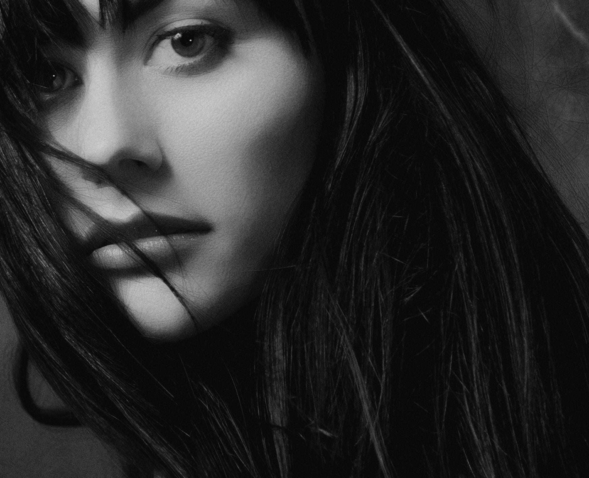 Woman with dark hair and intense gaze, captured in black and white.